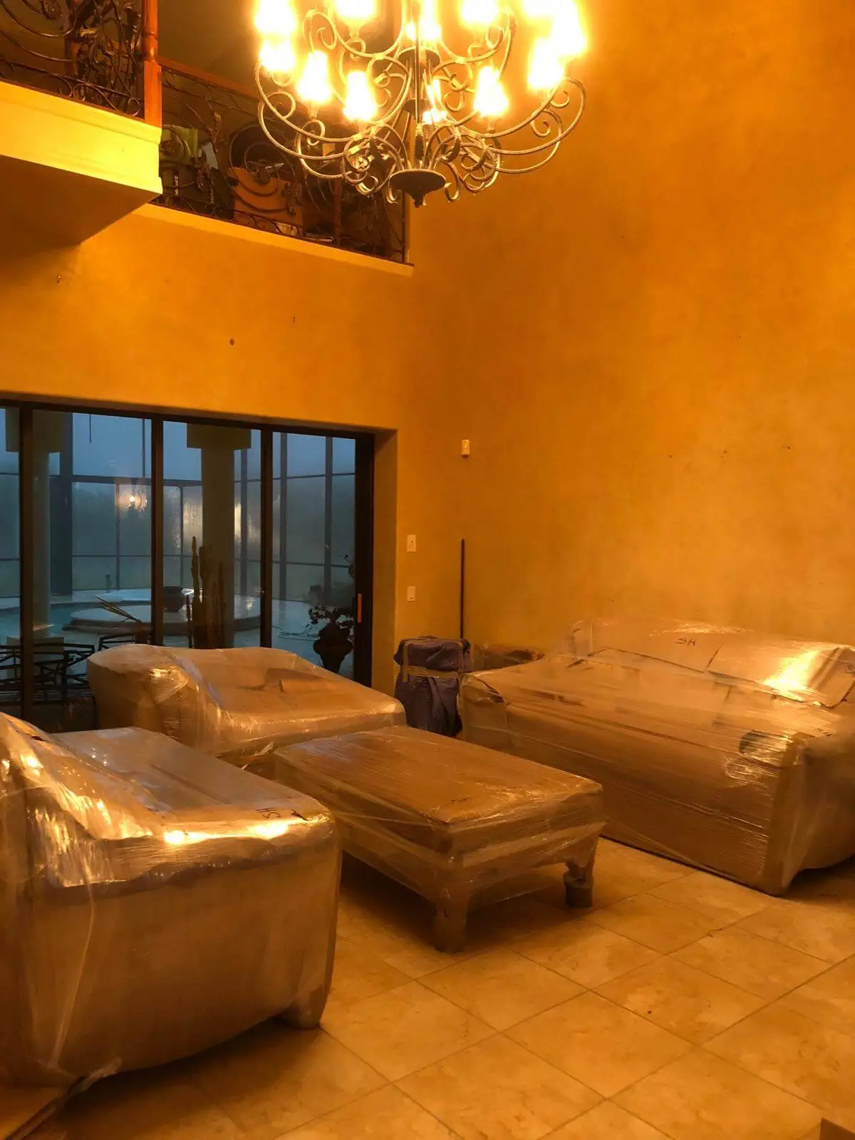 A living room of sofas and ottomans wrapped in kraft paper, ready to load.