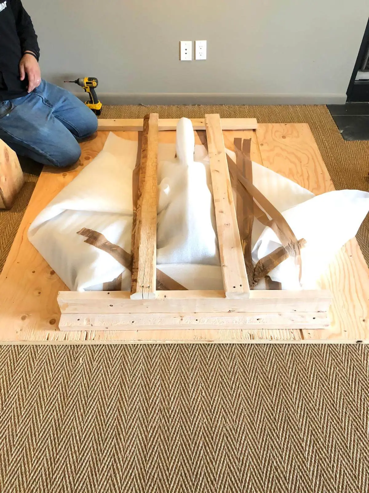 A crew member building a crate base around white-wrapped furniture legs.