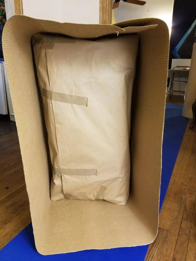 An armchair inverted with its seat papered and taped for transit.