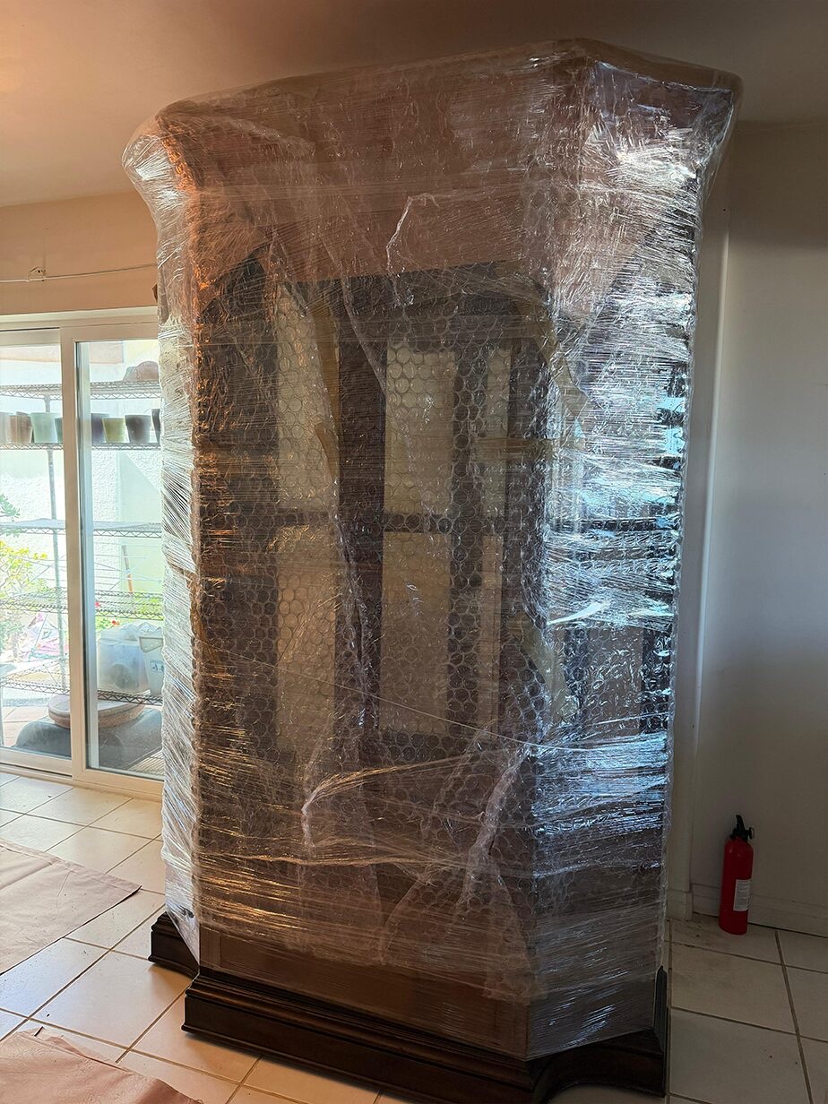 A tall cabinet fully stretch-wrapped in place before the move.