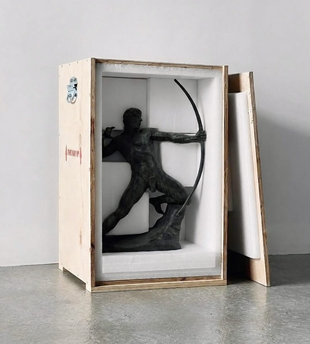 A bronze archer sculpture seated in a custom crate lined with white foam, the lid propped alongside.